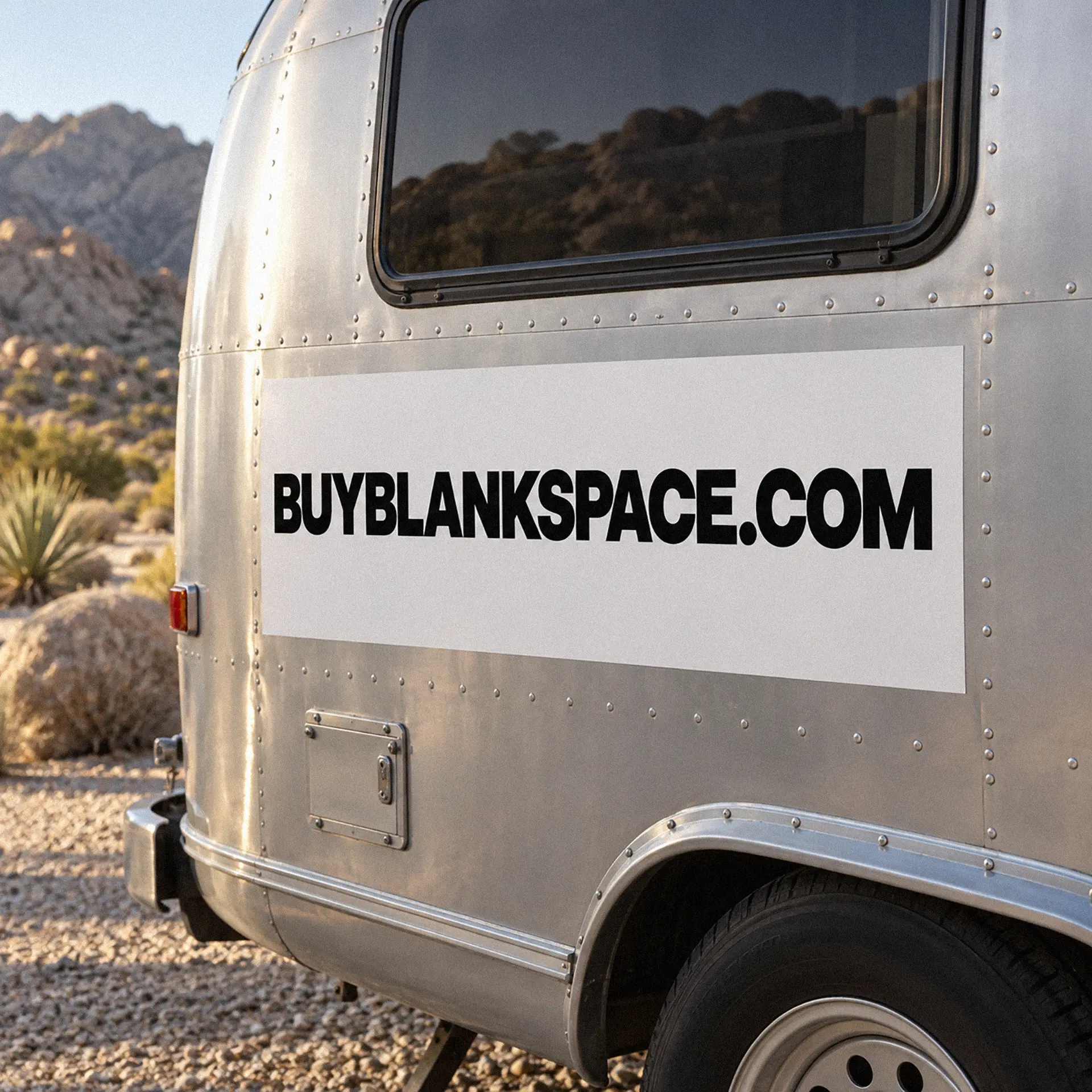 Travel trailer displaying BUYBLANKSPACE.COM in a desert setting